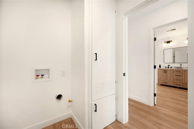 washroom with hookup for a washing machine, baseboards, visible vents, and light wood finished floors