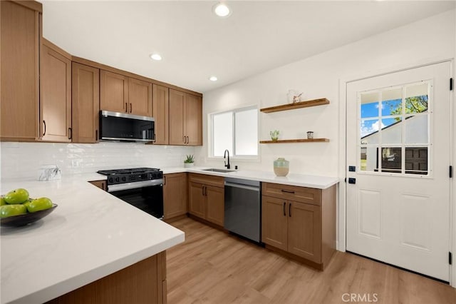 kitchen featuring appliances with stainless steel finishes, light countertops, a sink, and light wood finished floors