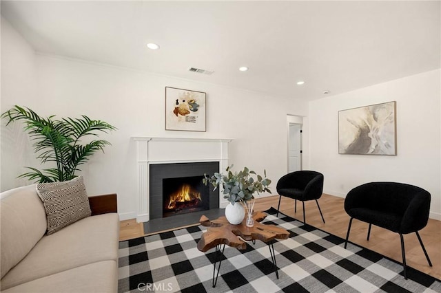 living room with a fireplace with flush hearth, visible vents, wood finished floors, and recessed lighting