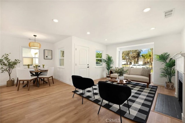 living area featuring a fireplace with flush hearth, light wood-type flooring, visible vents, and recessed lighting