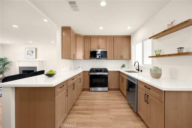 kitchen with stainless steel appliances, a peninsula, a sink, visible vents, and tasteful backsplash