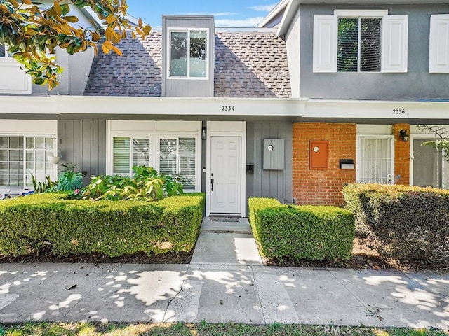 property entrance featuring brick siding and roof with shingles