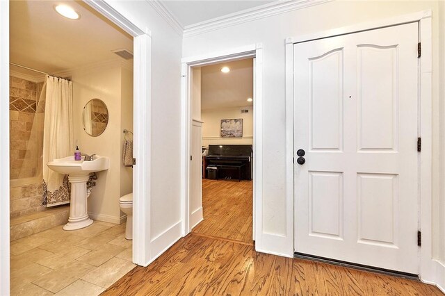 hall featuring baseboards, visible vents, ornamental molding, and wood finished floors