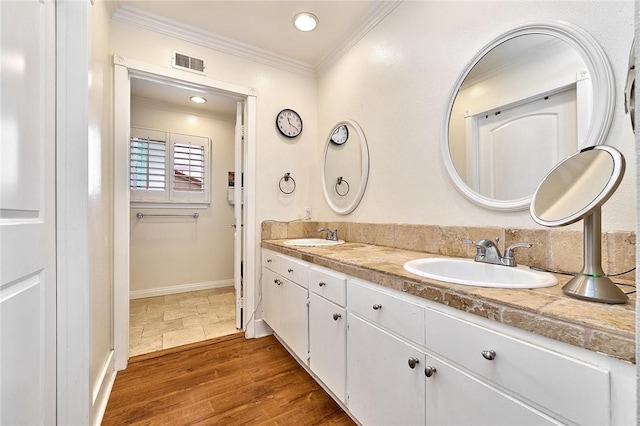 full bathroom with wood finished floors, a sink, visible vents, ornamental molding, and double vanity