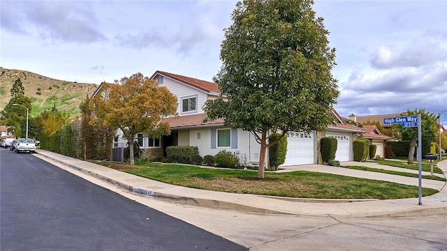 view of front of house featuring stucco siding, a garage, driveway, a tiled roof, and a front lawn