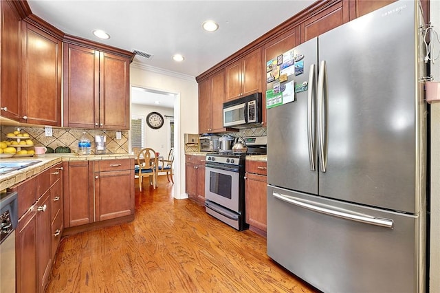 kitchen featuring stainless steel appliances, visible vents, ornamental molding, light wood-type flooring, and tasteful backsplash