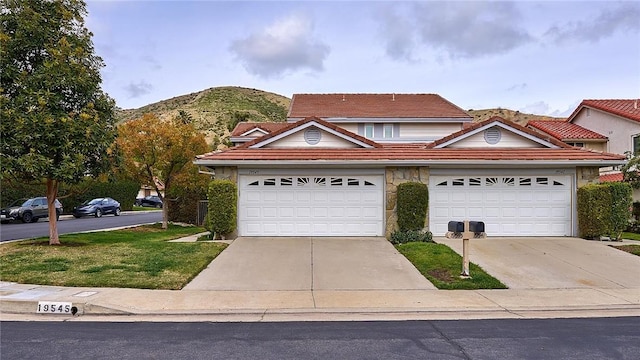 traditional home with driveway, a tile roof, a garage, and a mountain view