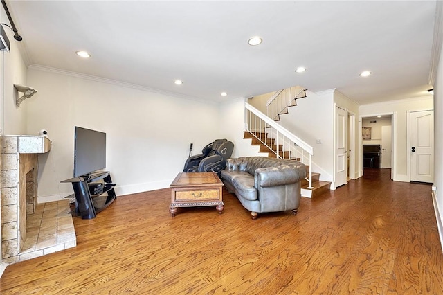 living room with crown molding, a fireplace, stairway, and wood finished floors