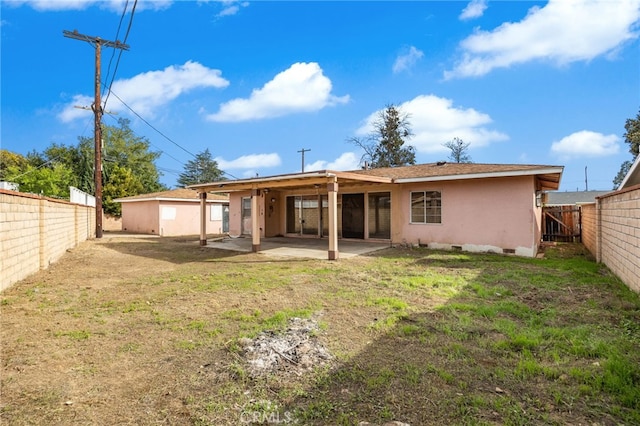 back of house featuring a patio, a fenced backyard, crawl space, a lawn, and stucco siding