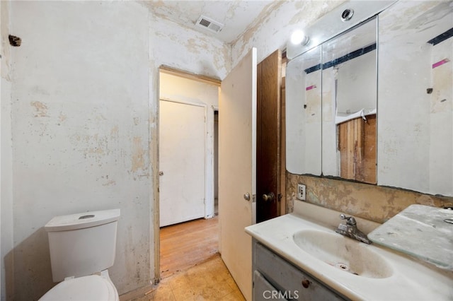 half bath with visible vents, vanity, toilet, and tile patterned floors