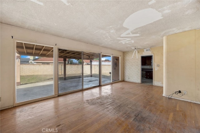 unfurnished room with visible vents, a textured ceiling, and hardwood / wood-style floors