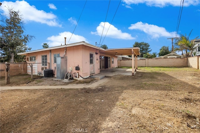 rear view of house with a patio, central AC unit, a fenced backyard, stucco siding, and a carport