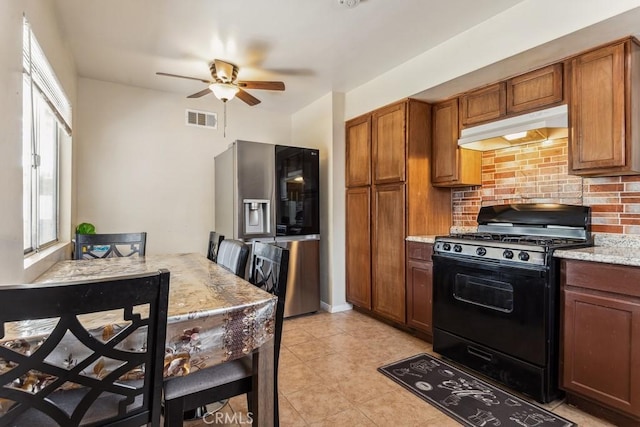 kitchen with brown cabinets, visible vents, decorative backsplash, black gas stove, and under cabinet range hood