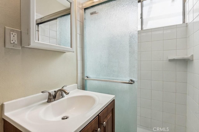 bathroom featuring a textured wall, a shower stall, and vanity