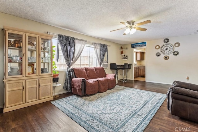 living area with dark wood-type flooring, baseboards, and a ceiling fan