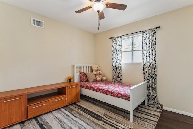 bedroom featuring a ceiling fan, baseboards, visible vents, and wood finished floors