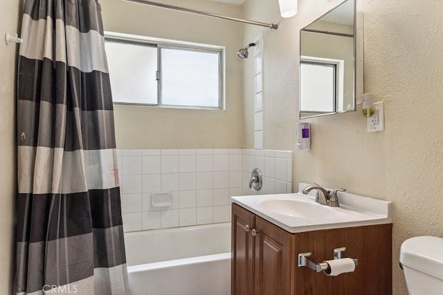 bathroom with a textured wall, vanity, toilet, and shower / bath combo with shower curtain