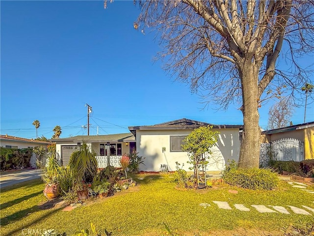 single story home with a front lawn, driveway, an attached garage, and stucco siding