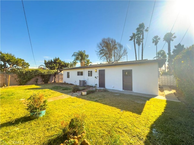 rear view of property with a lawn, fence, cooling unit, and stucco siding