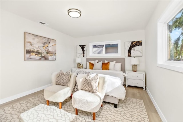 bedroom featuring light wood-style floors, visible vents, and baseboards