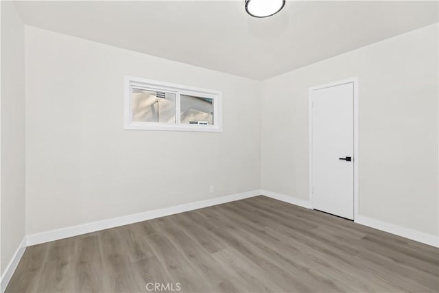 spare room with baseboards and wood finished floors