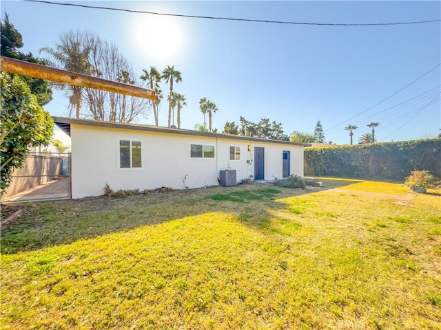 back of property with cooling unit, a yard, fence, and stucco siding