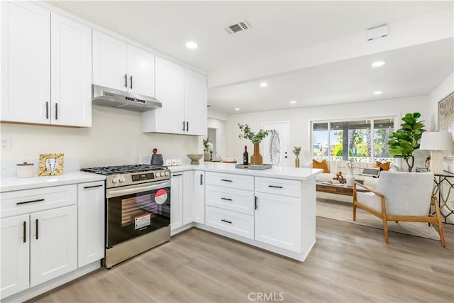 kitchen with under cabinet range hood, a peninsula, visible vents, light wood-style floors, and stainless steel gas range