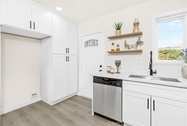 kitchen with light countertops, stainless steel dishwasher, a sink, and white cabinets