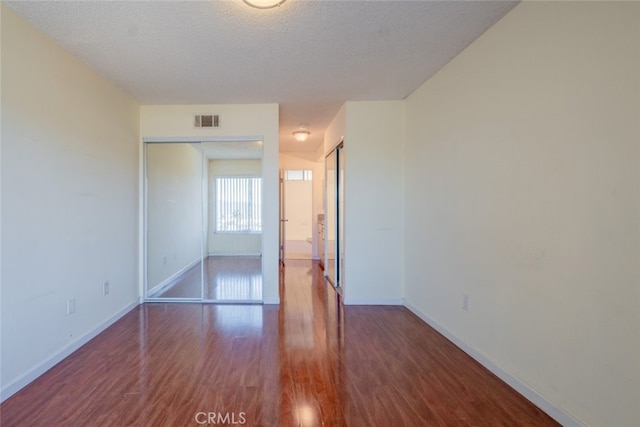 unfurnished bedroom with visible vents, baseboards, a textured ceiling, and wood finished floors