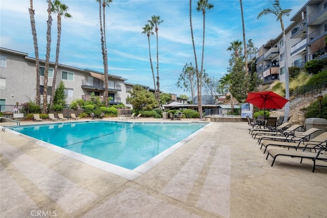 community pool with a patio and fence