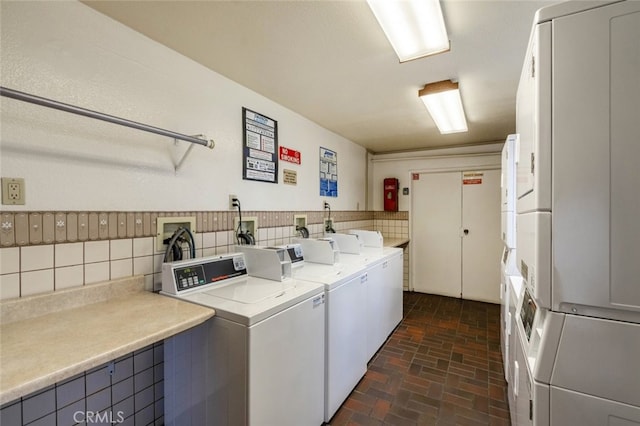 community laundry room with independent washer and dryer, stacked washer / drying machine, and brick floor