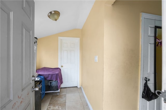 interior space with lofted ceiling, light tile patterned flooring, and baseboards