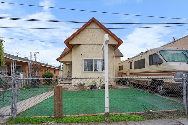 view of front facade with stucco siding, a front lawn, and fence