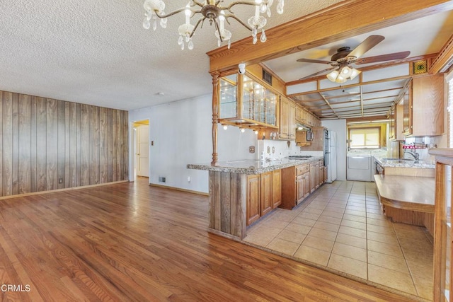 kitchen featuring gas cooktop, brown cabinetry, light wood-type flooring, and washing machine and dryer