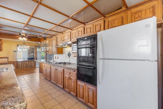 kitchen featuring stainless steel gas cooktop, dobule oven black, freestanding refrigerator, light tile patterned flooring, and under cabinet range hood