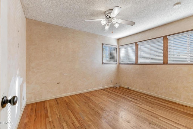 empty room featuring baseboards, a textured ceiling, a ceiling fan, and wood finished floors