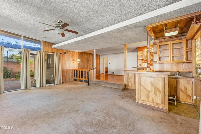 interior space featuring carpet floors, wood walls, a textured ceiling, a sink, and wet bar