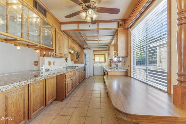 kitchen with light tile patterned floors, gas cooktop, visible vents, washer and dryer, and backsplash