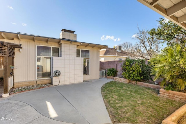 exterior space with fence, a lawn, and a patio