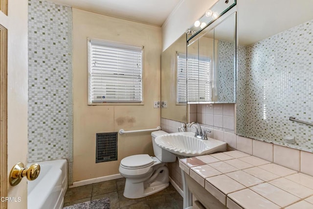 bathroom featuring toilet, tile patterned floors, a sink, a bathtub, and backsplash