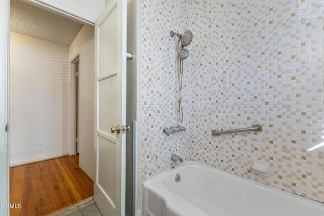 full bathroom with a textured ceiling, wood finished floors, and bathing tub / shower combination