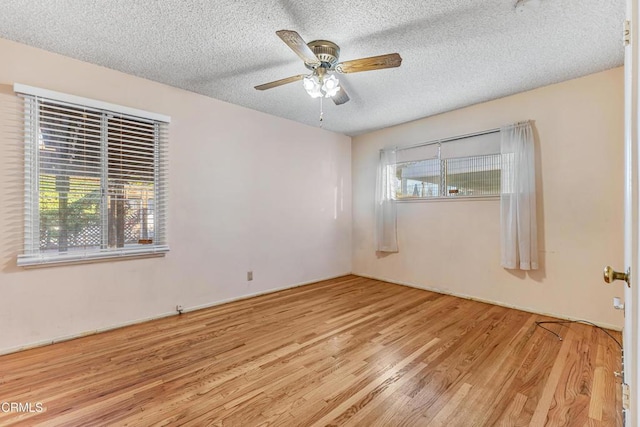 spare room featuring a textured ceiling, ceiling fan, plenty of natural light, and wood finished floors