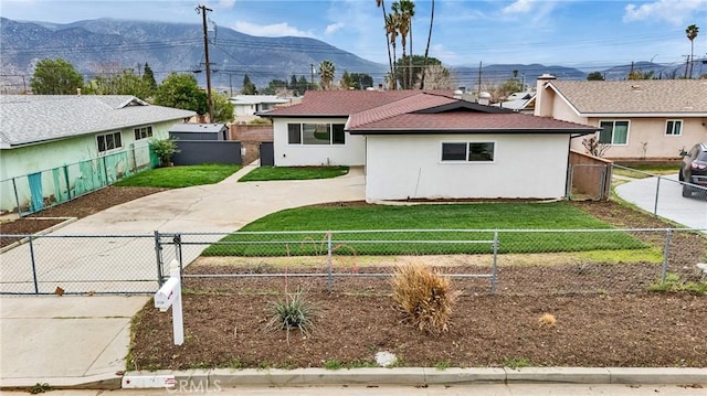 view of front of house featuring a fenced front yard, stucco siding, a gate, driveway, and a front lawn