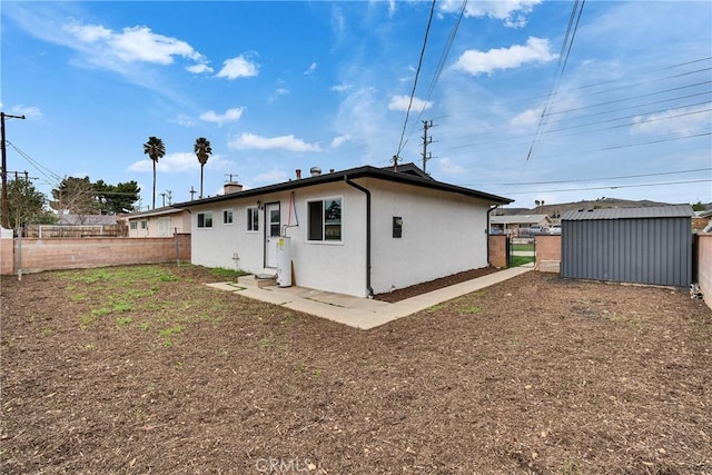 back of property featuring an outbuilding, fence, and stucco siding