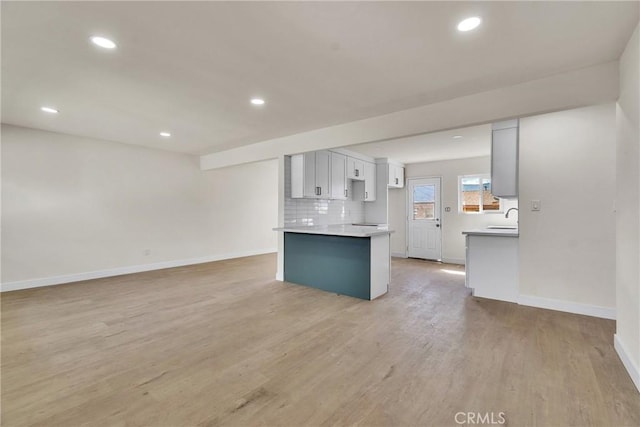 kitchen featuring recessed lighting, light countertops, decorative backsplash, light wood-style floors, and baseboards