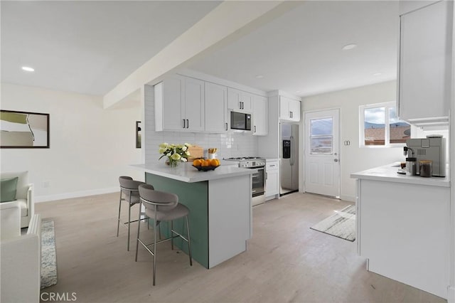 kitchen with decorative backsplash, gas range, black microwave, stainless steel fridge, and a kitchen breakfast bar