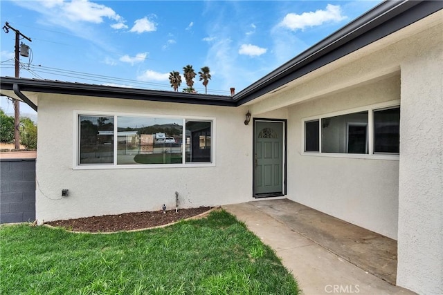 property entrance with a yard and stucco siding