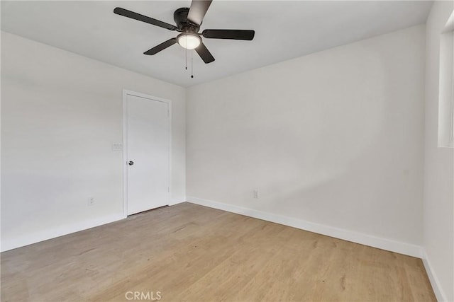 empty room featuring baseboards, ceiling fan, and light wood-style floors