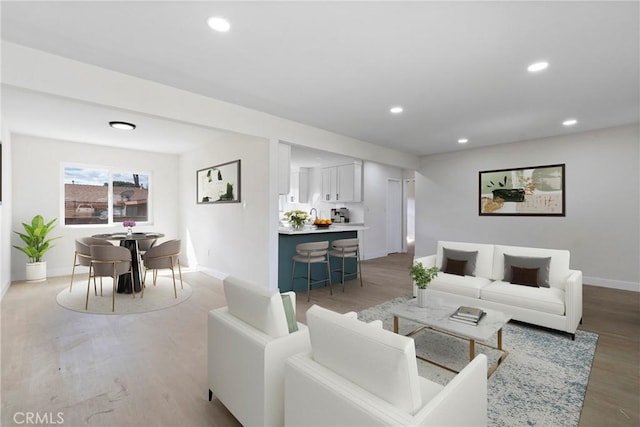 living room with light wood-style floors, baseboards, and recessed lighting