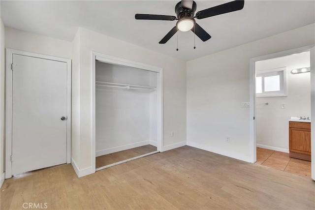 unfurnished bedroom with light wood finished floors, a closet, a ceiling fan, and baseboards